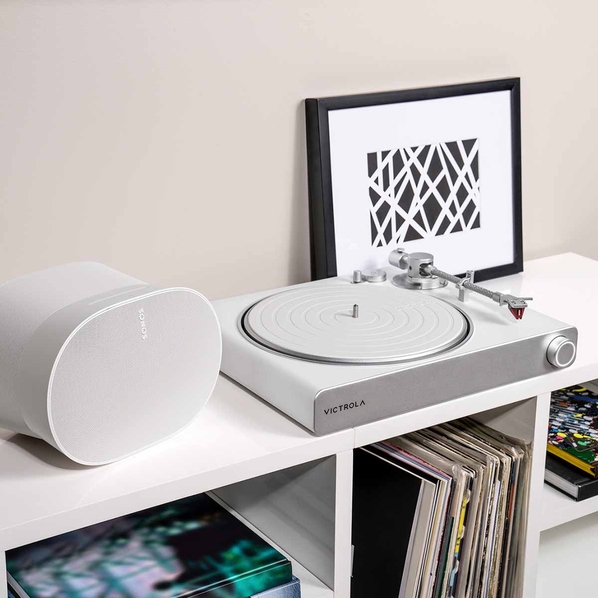 Victrola Stream Pearl Wi-Fi Streaming Turntable - white and silver - lifestyle shot front view angled right of unit on record cabinet with Sonos speaker to left