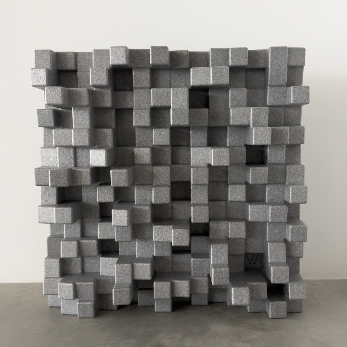 A grey 3D Vicoustic Cinema Multifuser DC4 Acoustic Diffuser Panel standing on a concrete floor against a plain light gray wall.