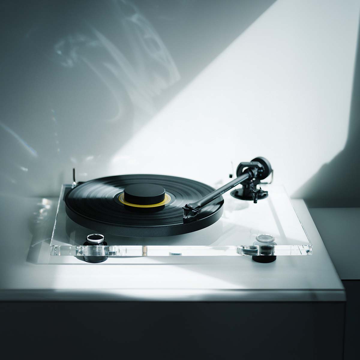 Pro-Ject XA B Balanced Acrylic Turntable - lifestyle shot high-angle front view of clear turntable on counter with sunlight reflected on back wall