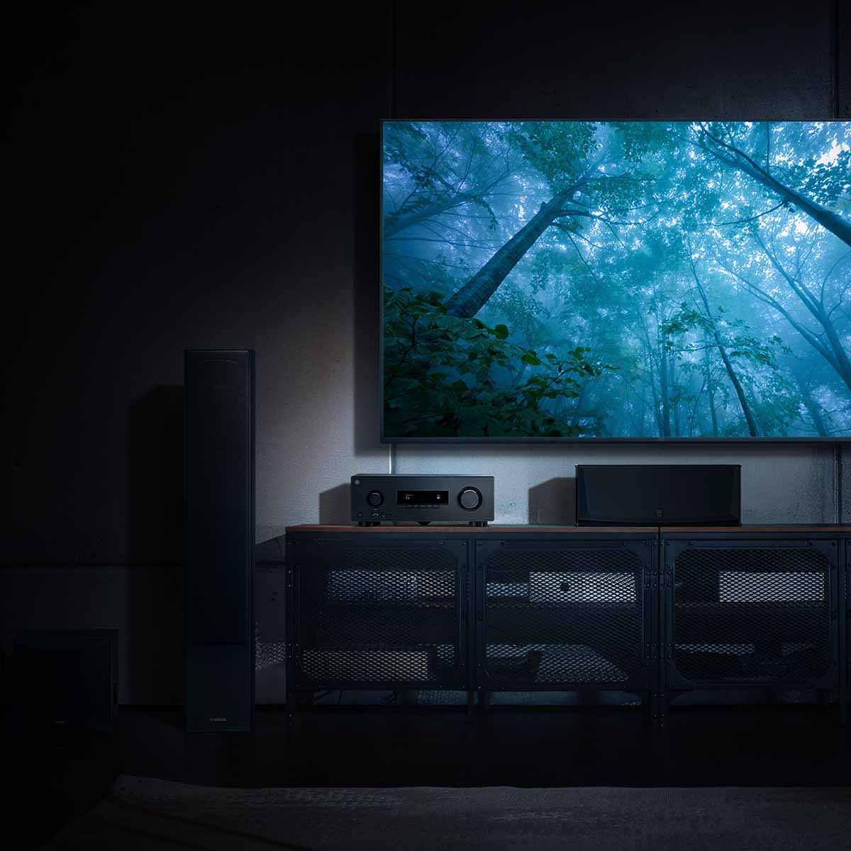 Yamaha RX500A 5.2-Channel AV Receiver - lifestyle image with dark lighting of unit on cabinet front view below TV