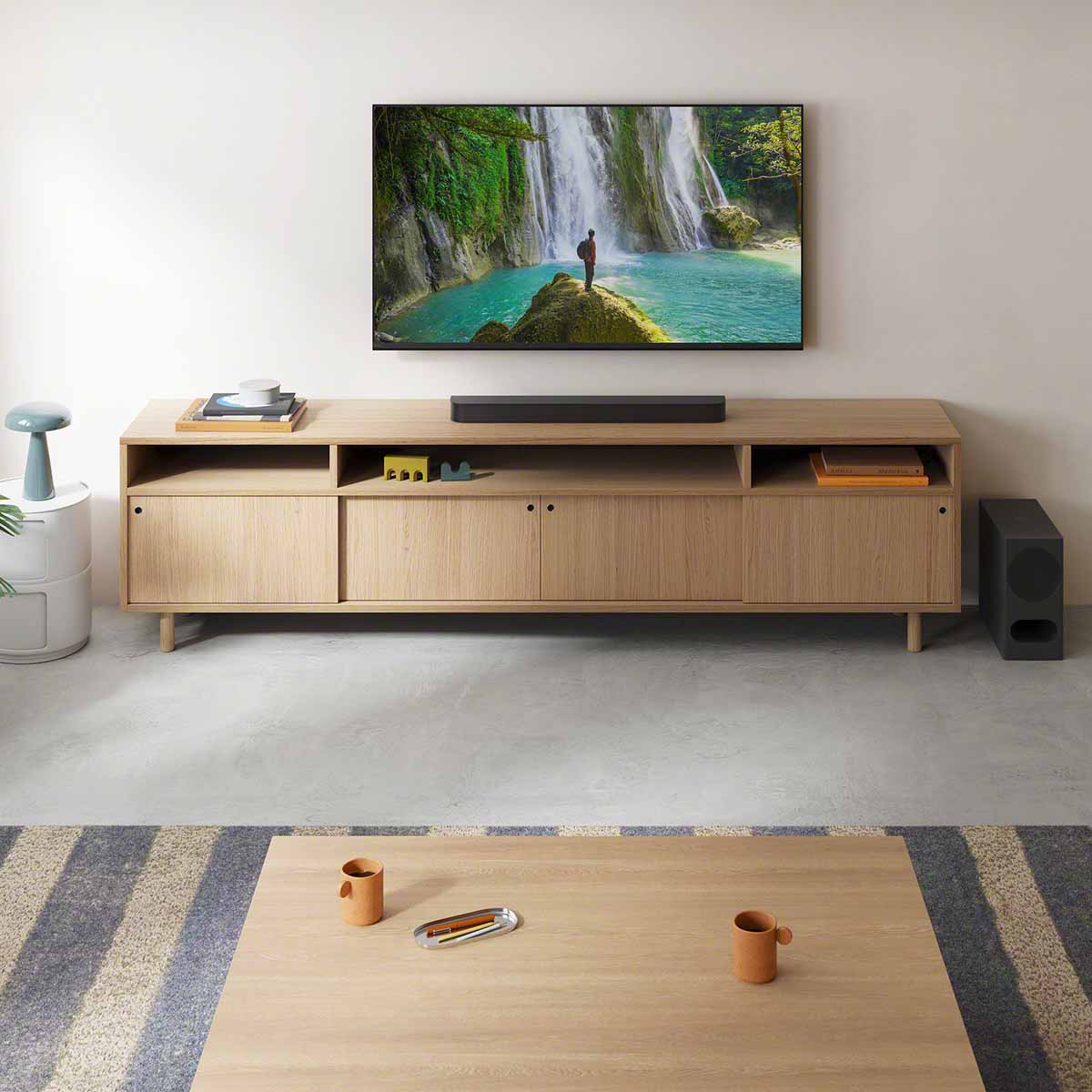 Sony BRAVIA Theater Bar 5 Soundbar lifestyle view of bar on cabinet under TV and subwoofer to right on floor