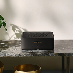 Marantz Model M1 Wireless Streaming Amplifier on a console table beside a turntable