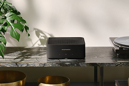 Marantz Model M1 Wireless Streaming Amplifier on a console table beside a turntable