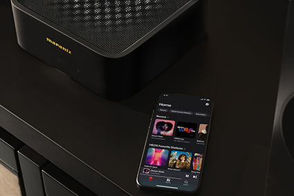 Marantz Model M1 Wireless Streaming Amplifier next to a smartphone with the Heos app open