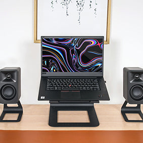 Kanto ORA Desktop Speakers on stands on either side of a laptop computer
