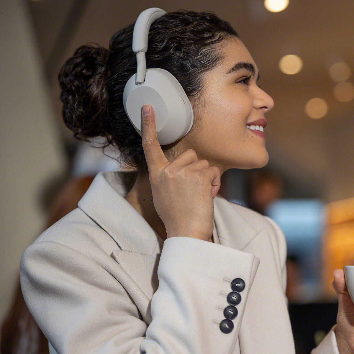 Lifestyle image of woman wearing silver Sony WH-1000MX5 headphones