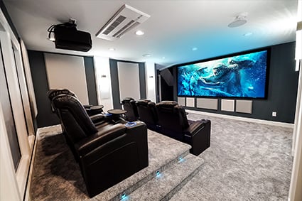 7.4.4 home theater with two rows of Audio Advice revolutions with Kong vs Godzilla playing on the screen