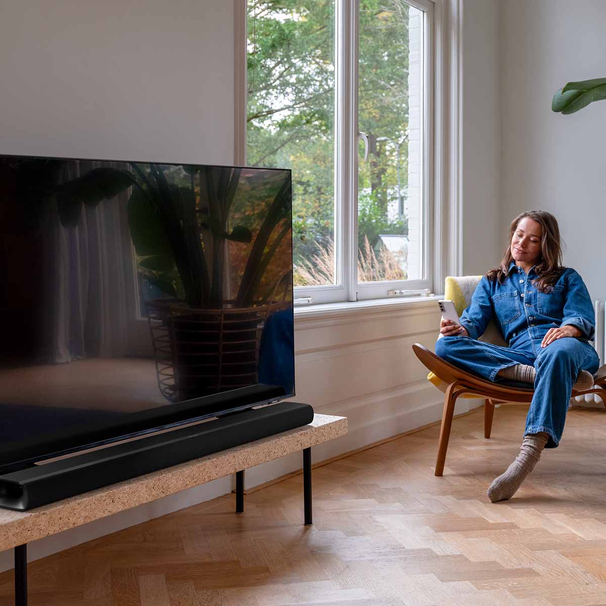 Harman Kardon Enchant 1100 Soudbar lifestyle photo with soundbar in front of tv to left