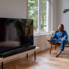 Harman Kardon Enchant 1100 Soudbar lifestyle photo with soundbar in front of tv to left