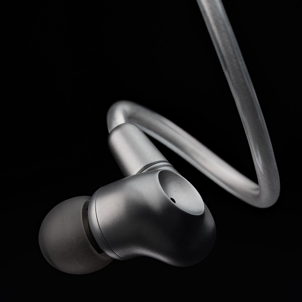 Meze Audio ASTRU Single Dynamic Driver In-Ear Monitors - artistic photo of single earbud connected to cable with eartip on black background