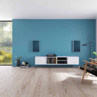 Lyngdorf FR-1 Speaker lifestyle shot front view pair of white units with blue grilles mounted on blue wall above white cabinet