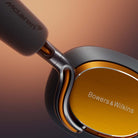 Bowers & Wilkins Px8 S2 McLaren Edition Wireless Over-Ear Headphones - detail of side showing McLaren and Bowers & Wilkins logos on orange background
