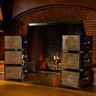 REL Acoustics Carbon Special Black Label Subwoofer lifestyle shot 2 stacks of three units with grilles on either side of fireplace