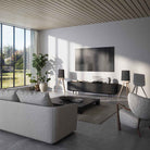 Lyngdorf Cue-100 Speaker lifestyle photo of speakers in living room, pair of speakers with oak base and black grilles