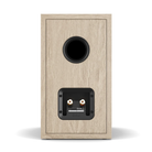 A single bookshelf speaker shown from the rear, featuring a light oak wood-grain finish and a black circular port and rear terminal plate, set against a plain white background.
