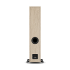 A tall, narrow Dali Sonik 7 floor-standing speaker with a light oak wood-grain finish and a black circular driver and front baffle, shown from the back on a white background.