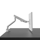 Monitor arm attached to a desk with a white background