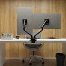 Modern office setup with a desk, chair, and computer monitors on a wooden wall background