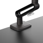 Black adjustable desk lamp on a gray surface with a white background