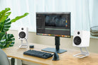 Modern home office setup with a computer monitor, keyboard, and speakers on a desk.