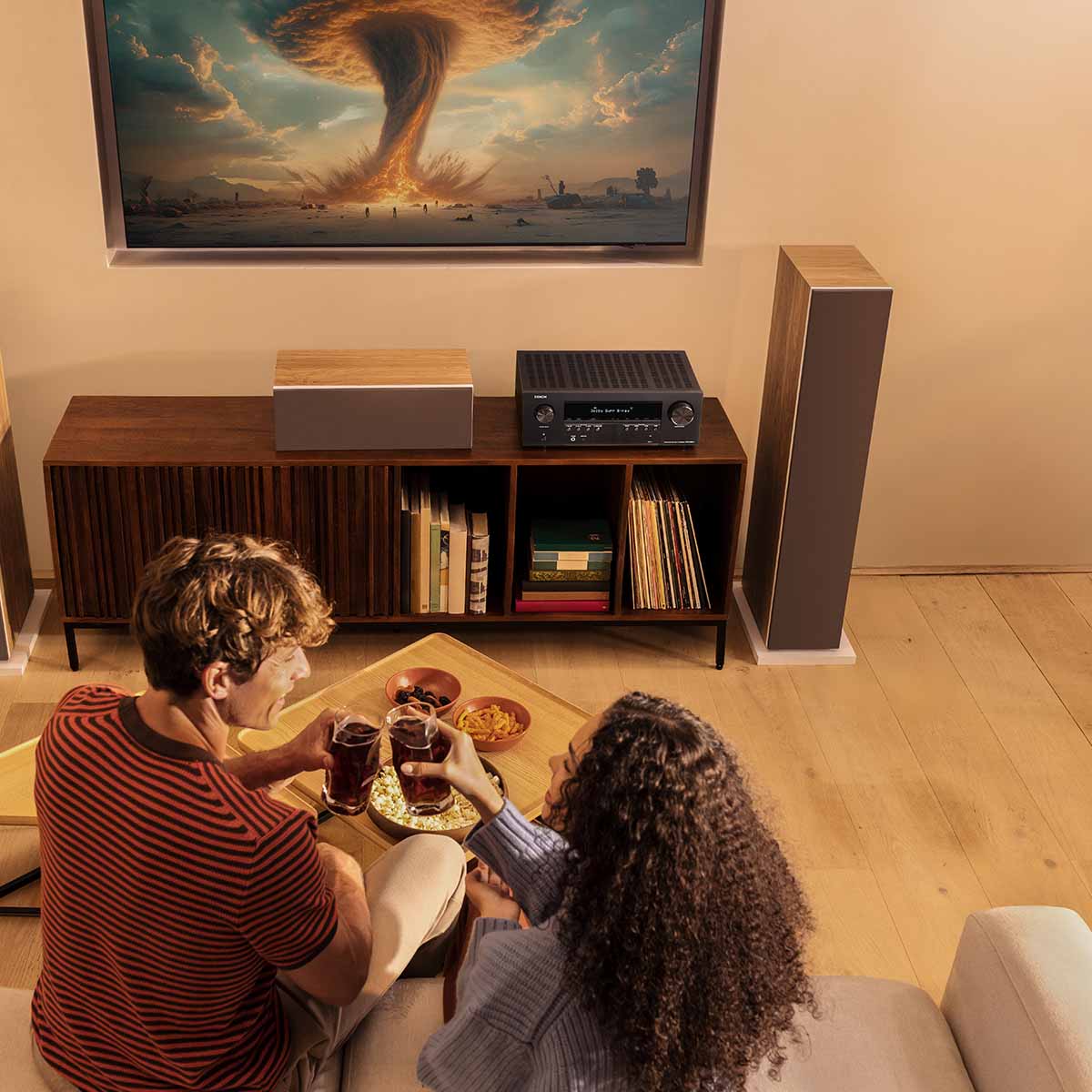 Denon AVR-S980H AV Receiver lifestyle photo of unit on cabinet with two people eating on couch