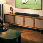 Devialet Dione Dolby Atmos Soundbar - lifestyle photo of soundbar on cabinet under TV showing soccer