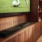 Devialet Dione Dolby Atmos Soundbar - lifestyle photo of soundbar on cabinet under TV showing soccer