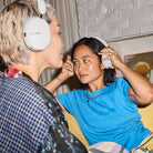 Sonos Ace Ultra Wireless Over-Ear Headphones - lifestyle photo of two women wearing white headphones sitting on a couch