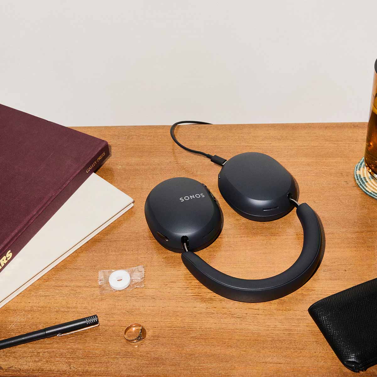 Sonos Ace Ultra Wireless Over-Ear Headphones - lifestyle photo of black headphones charging on a desk
