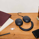Sonos Ace Ultra Wireless Over-Ear Headphones - lifestyle photo of black headphones charging on a desk