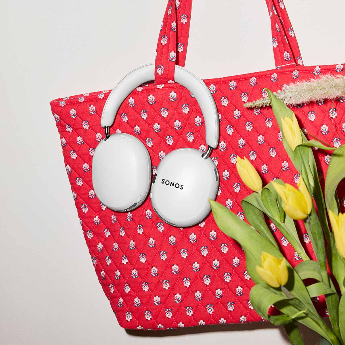 Sonos Ace Ultra Wireless Over-Ear Headphones - lifestyle photo of white headphones hanging from a red tote bag