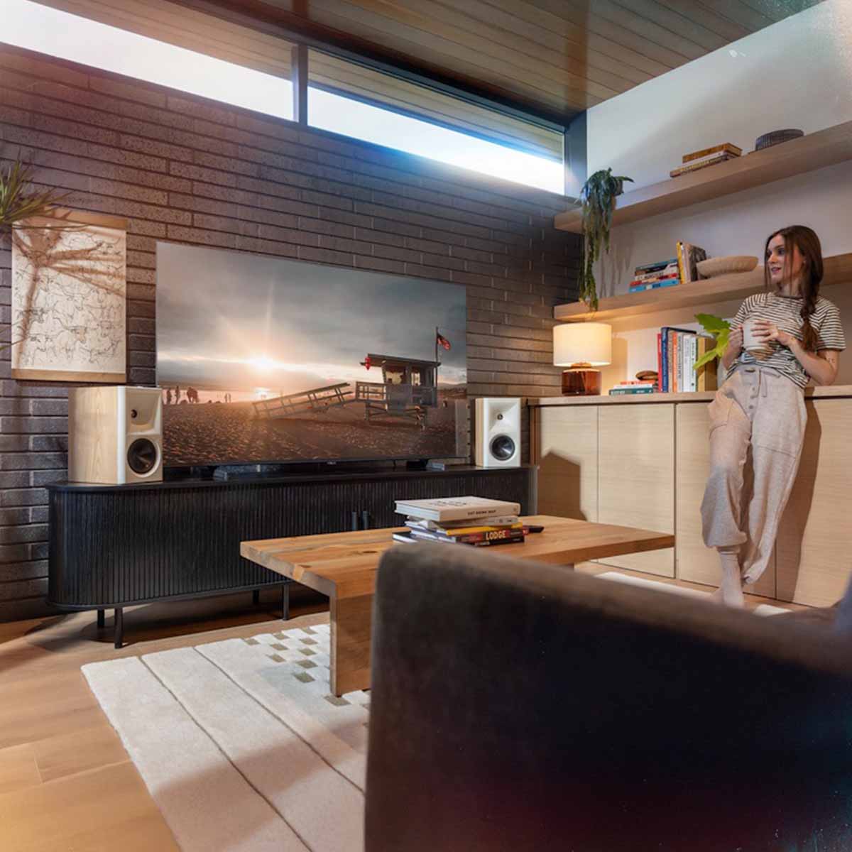 Klipsch The Fives II Dolby Atmos 5.25" Powered Speakers - Pair - lifestyle photo pair of red oak speakers on cabinet with woman to right of room