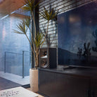 Klipsch The Fives II Dolby Atmos 5.25" Powered Speakers - single speaker - lifestyle photo single ebony speaker on cabinet with tv to right