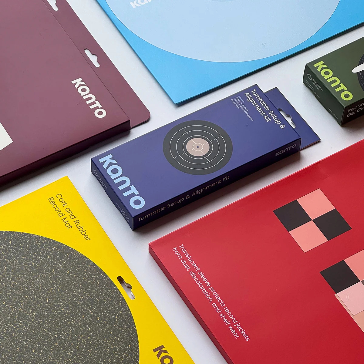Several Kanto brand product boxes and packaging pieces arranged on a white surface, including a blue box labeled 'Turntable Setup and Alignment Kit' and other colorful boxes in maroon, yellow, green, and red.