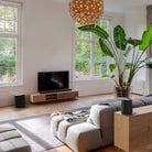 Harman Kardon Enchant 1100 Soudbar lifestyle photo with soundbar in front of TV, sub on floor to left and speaker behind couch