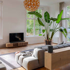 Harman Kardon Enchant 1100 Soudbar lifestyle photo with soundbar in front of TV and speaker behind couch