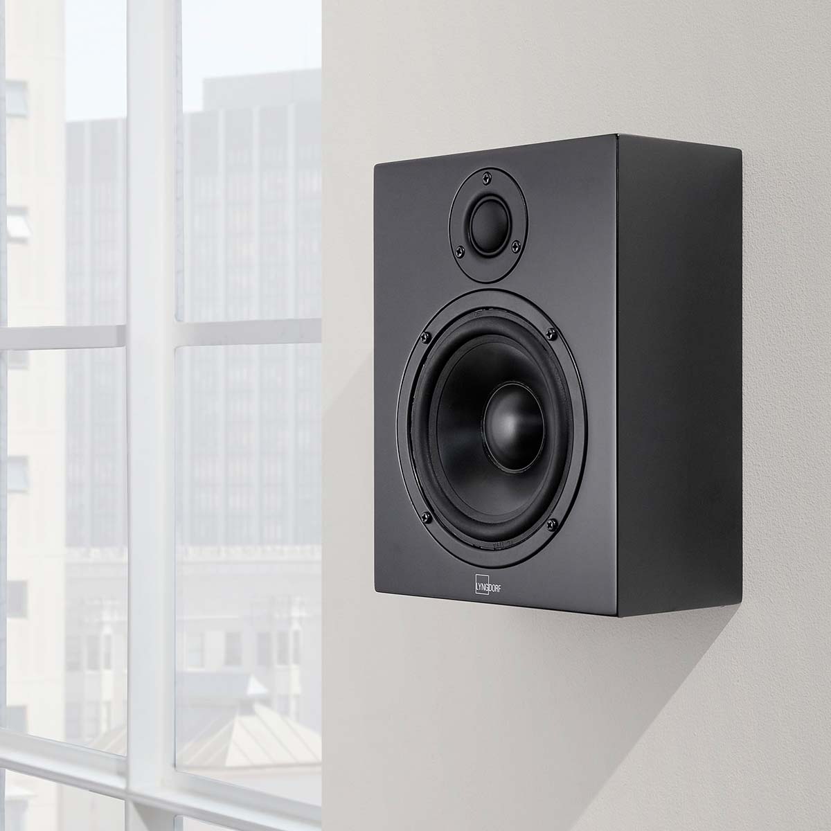 Lyngdorf MH-2 Satellite Speaker lifestyle shot black speaker without grille mounted on wall