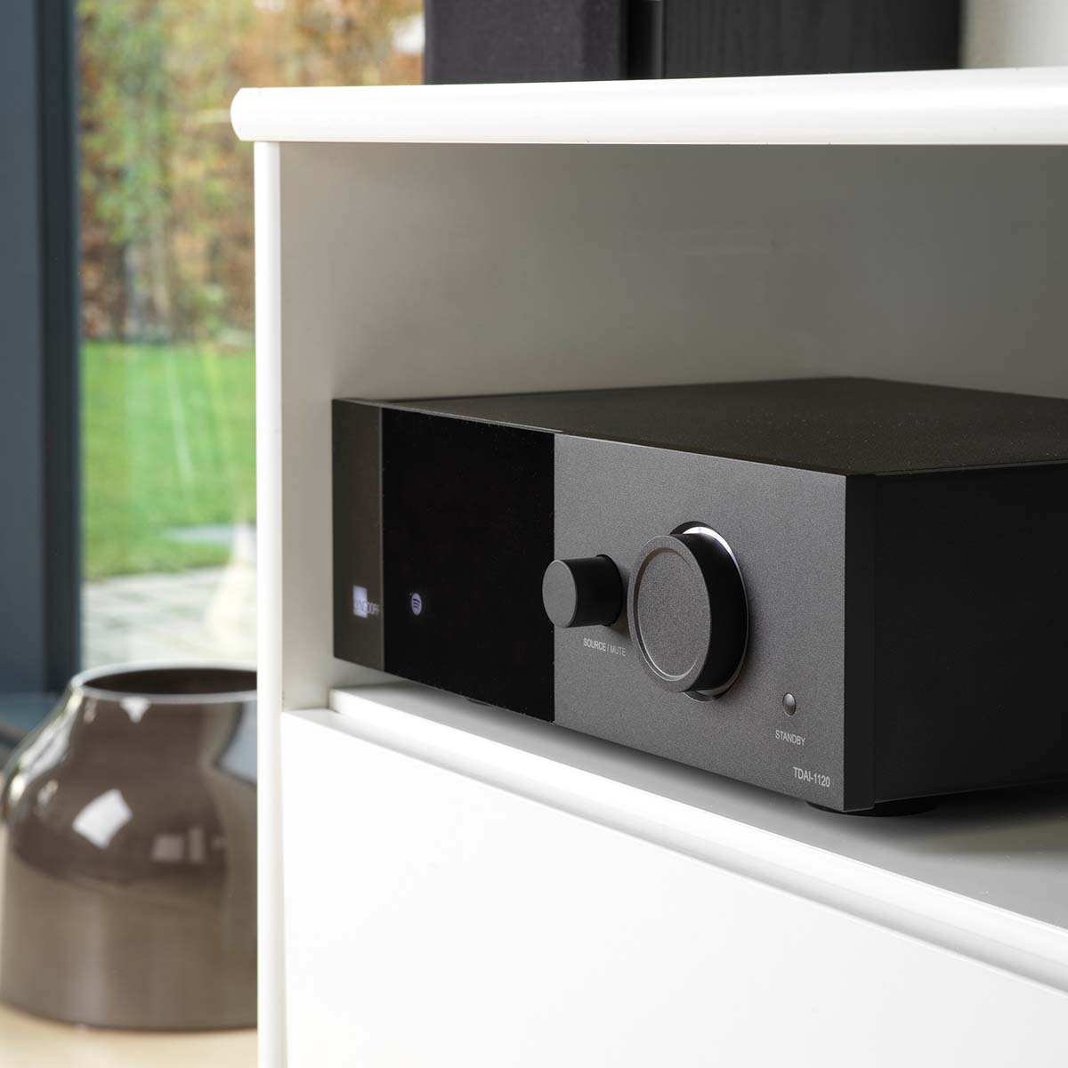 Lyngdorf TDAI-1120 Compact Streaming Amplifier with RoomPerfect lifestyle view of unit in cabinet