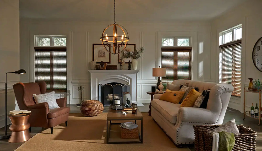 Living room with a fireplace, sofa, and armchair with wooden motorized blinds on the windows