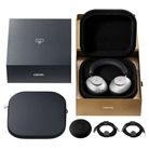 Loewe over-ear headphones shown with their branded packaging and accessories on a white background. The set includes a black hard case with silver interior padding holding the headphones, a black retail box with the Loewe name and heart logo, a separate black zippered case, a round black foam insert, and two black cable accessories.