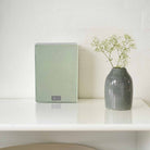 Lyngdorf MH-3 white Satellite Speaker front view lifestyle shot with pastel green grille