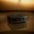 A black Marantz Cinema 50 Series 2 AV Receiver unit with front control knobs, photographed on a reflective surface against a warm golden-brown studio background.