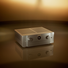 A silver and gold Marantz Cinema 50 Series 2 AV Receiver with two front rotary knobs and a central display, set on a reflective dark surface against a warm golden-brown gradient background.