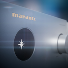 Close-up of a Marantz Cinema 60 Series 2 AV Receiver showing the gold Marantz logo and a circular black speaker grille with a white starburst emblem.