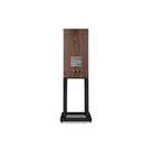 A single Mission 700 Bookshelf Speaker shown from the front on a clean white background. The speaker features a walnut wood cabinet on a black metal stand with a glass front.