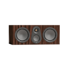 A three-way in-wall speaker with a dark brown wood grain finish, featuring two large front woofers and a central waveguide with a small dome tweeter and a larger grille port.