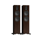 A pair of tall Monitor Audio Silver Silver 500 8G 3-way Floor Standing Speaker with dark brown wood-grain fronts, black circular driver cones, and small black feet, shown on a plain white background.