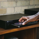 NAD C 589 CD Player - lifestyle photo detail of hand placing disc into open tray