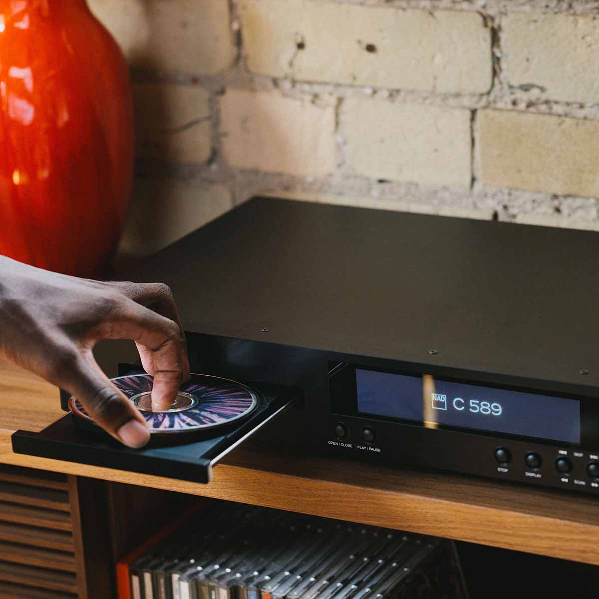 NAD C 589 CD Player - lifestyle photo detail of hand placing disc into open tray