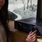 Onkyo Muse Y-40 Network Integrated Amplifier - Black - lifestyle view of unit on cabinet with woman adjusting dial